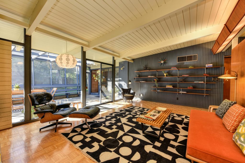 pexels-photo-18657168-18657168 Stylish mid-century modern living room with armchairs, shelves, and natural light.